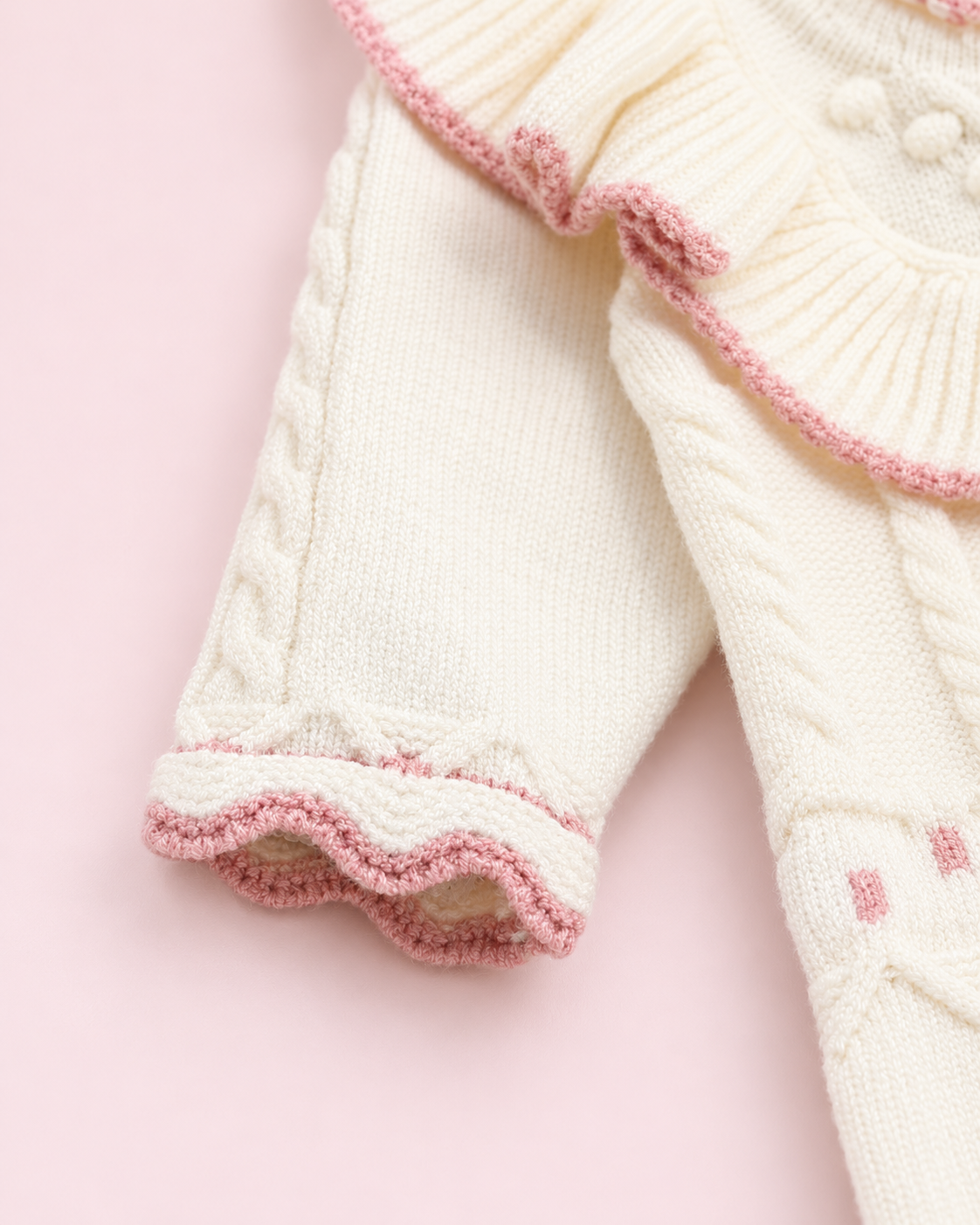 Close-up of cream knit sleeve with pink scalloped cuff