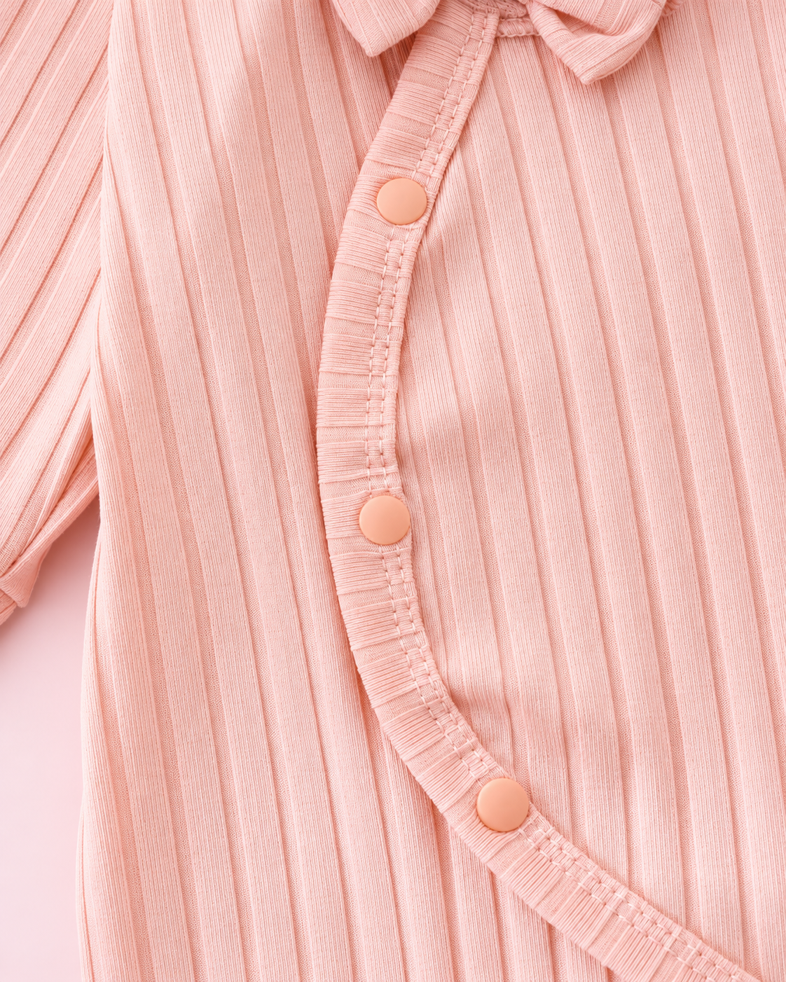 Curved snap fastening on light pink ribbed romper